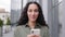 Latin Caucasian Hispanic smiling woman success businesswoman using cell phone smartphone app Wi-Fi device outdoors