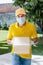 Latin delivery man with mask holding and carrying a cardbox in quarantine coronavirus pandemic