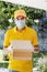 Latin delivery man with mask holding and carrying a cardbox in quarantine coronavirus pandemic