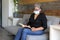 Latin grandmother with protection mask reading book in waiting room