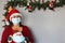 Latin grandmother with protection mask and santa claus hat, christmas decoration and santa claus doll, new normal covid-19
