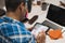 Latin graphic designer working in his office on an illustration tablet, he wears a blue checkered shirt and glasses