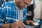 Latin graphic designer working in his office on an illustration tablet, he wears a blue checkered shirt and glasses