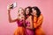 Latin happy girl sending air kiss. Charming ladies making selfie on pink background