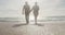 Latin hispanic couple holding hands, walking on beach at sunset