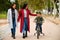 Latin lesbian couple walking in a park with their son in a bicycle.