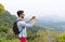 Latin Man With Backpack Take Photo Of Landscape From Mountain Top On Cell Smart Phone