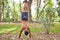 Latin man leaning on hands and feet upwards. The man is shirtless and doing the pine tree in a park with dry leaves