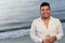 Latin man walking with a glass of white wine by the seashore