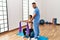 Latin man and woman wearing physiotherapist uniform having rehab session using fit ball and elastic band at rehab center