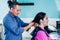 Latin man working as a hairdresser and cutting hair of a female customer in a beauty salon small business in Mexico city