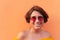 Latin mature woman with yellow blouse and sunglasses on orange background