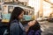 Latin mother and daughter looking affectionately outside on a Lisbon street, in the background there is a classic tram from