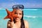 Latin tourist girl holding starfish tropical beach