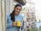 Latin woman drinking cup of coffee or tea smiling happy at apartment window balcony