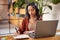 Latin woman with headset writing notes during video call