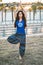 Latin woman in Indian clothes does a yoga posture in a park at dusk