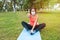 Latin woman with mask facing the camera while stretching on the ground and doing a gesture to be fine with the finger in a park