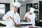 Latin woman pastry chef wearing uniform holding a bowl preparing delicious sweets chocolates at kitchen in Mexico Latin America