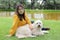 Latin woman with protection mask sitting on the grass with white dog, walking on the shore of the lake, new normal