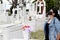 Latin woman with protection mask visiting pantheon to leave flower offering in tomb on the day of the dead in mexico