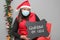 latin woman with santa claus hat and blackboard with message `stay at home` in Christmas decoration