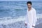 Latin young man white shirt walking blue beach