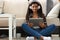 Latin young woman sit on carpet with tablet and watch show, lady in headset