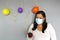 Latina with black hair with protection mask, cake, colored balloons celebrates birthday at home by quarantine and new normal covi