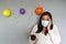 Latina with black hair with protection mask, cake, colored balloons celebrates birthday at home by quarantine and new normal covi