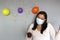 Latina with black hair with protection mask, cake, colored balloons celebrates birthday at home by quarantine and new normal covi