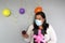 Latina with black hair with protection mask, cake, colored balloons celebrates birthday at home by quarantine and new normal covi