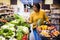 Latina choosing green lettuce in vegetable section of supermarket