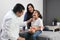 Latina mother cares for and accompanies her curly little daughter at the dark-haired pediatrician specialist doctor`s office to pr