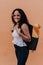 Latina teenager carrying backpack while standing in front of wall