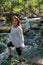 Latina woman smiling standing in the shade with glowing hair in a stream with waterfalls in the background