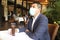 Latino adult man with protection mask in restaurant with drink and food, new normal covid-19
