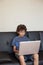 Latino boy sitting on sofa with laptop computer