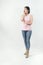 Latino female with a pink t-shirt and jeans acting surprised in a studio