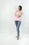 Latino female with a pink t-shirt and jeans acting surprised in a studio