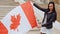 Latino girl activist with waving Canada nation flag in hands looking at camera and smiling FHD footage