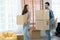Latino man with beard and Asian woman couple help to carry packed cardboard boxes into their new home where they were moving in
