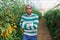 Latino man standing near tomatoes in glasshouse