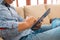 A Latino sitting on a couch and reading what`s new on his tablet computer