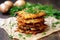 latkes stacked on parchment paper with a sprig of parsley on top