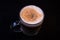 Latte with Foam in a Clear Glass Mug against a black background