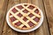 Lattice round cake with strawberry jam on wooden background