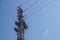 Lattice-type steel tower fragment over blue sky as a part of high-voltage line. Overhead power line details