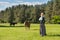 Latvian woman in traditional clothing posing on nature with horse in village.