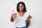 Laughing african young girl smiling during video call. Indoor photo of optimistic black lady making selfie on white background